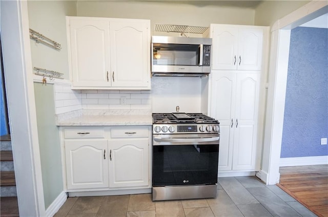 3220 48th St, Metairie, LA 70001 - kitchen featuring baseboards, white cabinets, light stone counters, backsplash, and stainless steel appliances