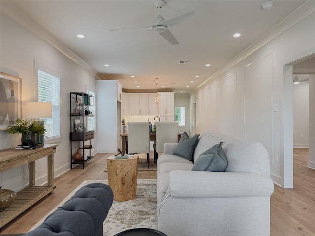 2412 Mississippi Ave, Metairie, LA 70003 - living room with a ceiling fan, light wood-style flooring, ornamental molding, recessed lighting, and a chandelier
