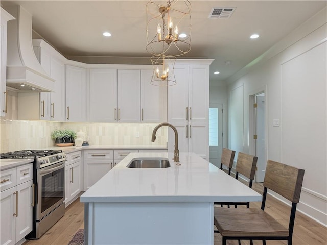 2412 Mississippi Ave, Metairie, LA 70003 - kitchen with stainless steel gas range oven, custom exhaust hood, backsplash, a kitchen island with sink, and recessed lighting