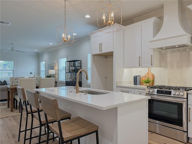 2412 Mississippi Ave, Metairie, LA 70003 - kitchen featuring premium range hood, stainless steel gas range oven, plenty of natural light, light wood-style flooring, and recessed lighting