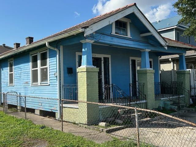 view of front facade with a porch, a fenced front yard, and a chimney