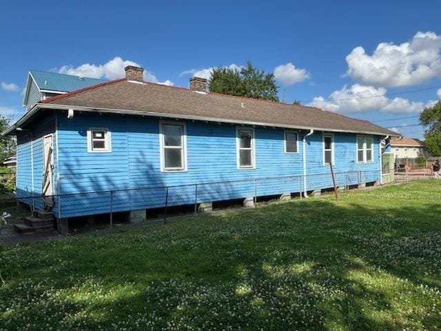 back of property with fence, a yard, and a chimney