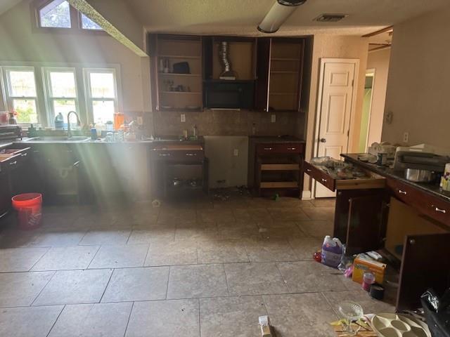 kitchen with a sink, open shelves, and backsplash