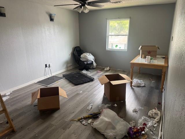 misc room featuring visible vents, a ceiling fan, baseboards, and wood finished floors