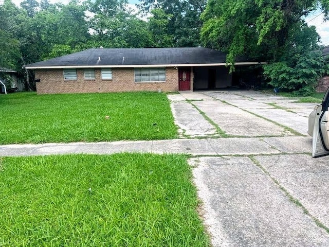 ranch-style house with brick siding, driveway, a carport, and a front lawn