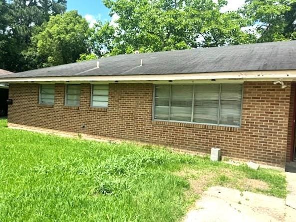 view of side of property featuring brick siding and a yard