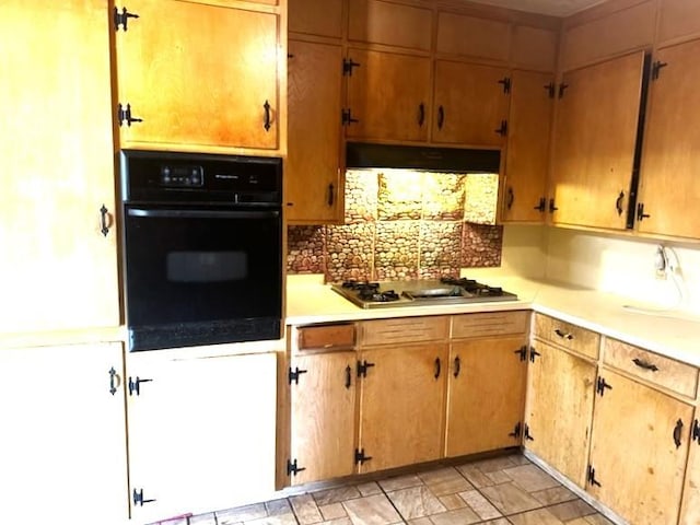 kitchen featuring light countertops, stainless steel gas cooktop, under cabinet range hood, and oven