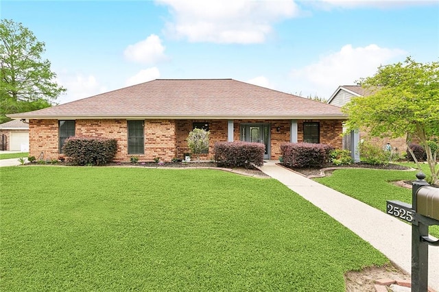 ranch-style home with brick siding, a shingled roof, and a front yard