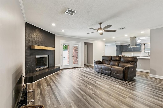 living area featuring crown molding, visible vents, baseboards, a textured ceiling, and a ceiling fan