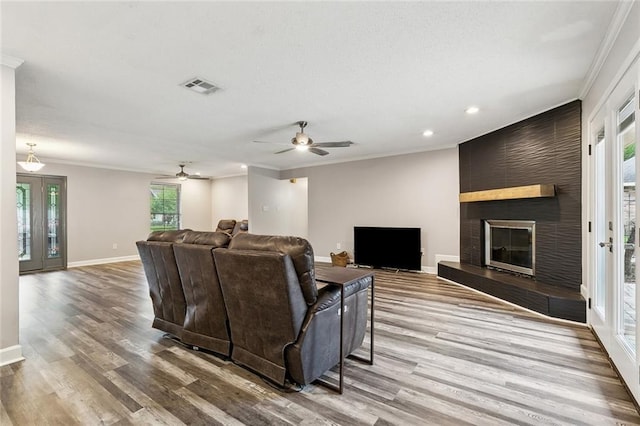 living room featuring crown molding, a ceiling fan, baseboards, recessed lighting, and wood finished floors