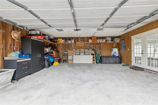 garage featuring wood walls, french doors, and a garage door opener