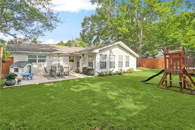 back of house featuring a patio, a fenced backyard, a playground, and a lawn