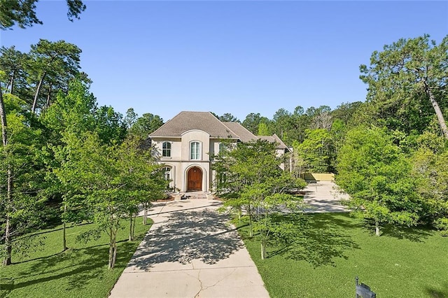 french provincial home featuring stucco siding and concrete driveway