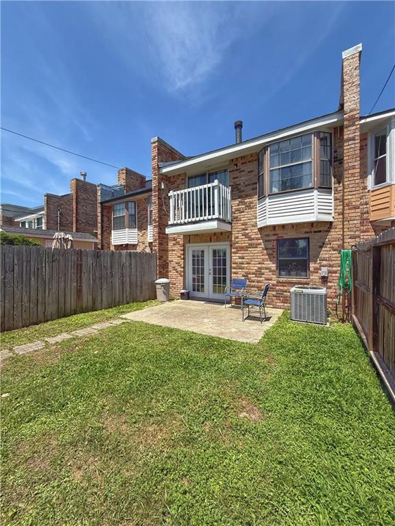 308 Ormond Meadows Dr Unit B, Destrehan, LA 70047 - rear view of house with french doors, a balcony, a fenced backyard, a yard, and a patio