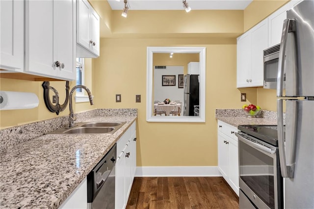 kitchen featuring baseboards, dark wood-type flooring, white cabinets, a sink, and appliances with stainless steel finishes