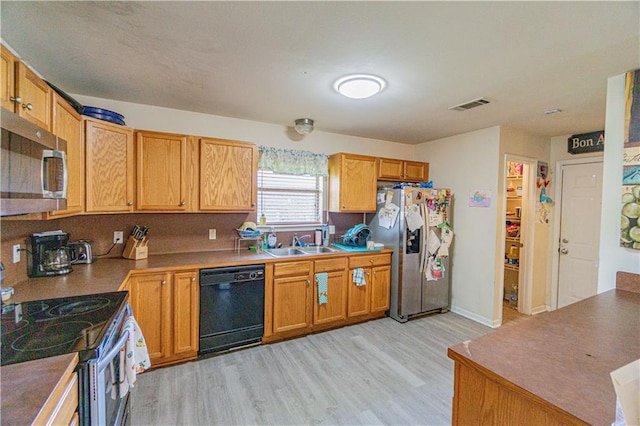 11257 Abbey Ln, Denham Springs, LA 70726 - kitchen with appliances with stainless steel finishes, a sink, light wood finished floors, brown cabinetry, and visible vents