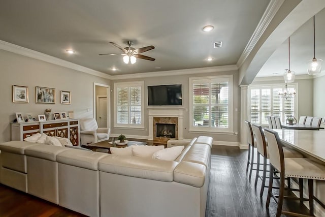 living area with visible vents, a high end fireplace, crown molding, ceiling fan with notable chandelier, and recessed lighting