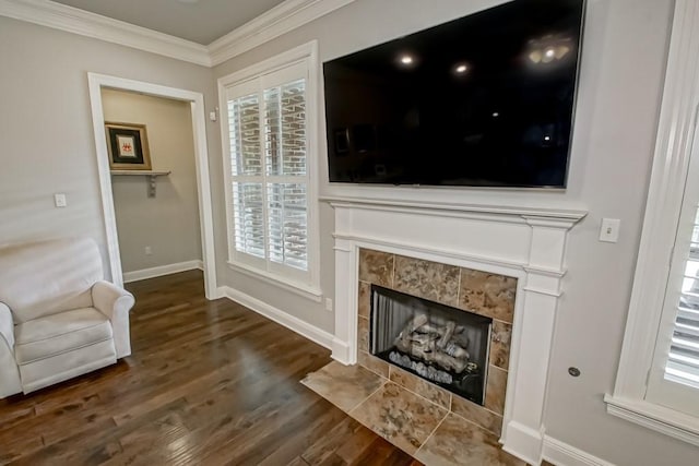 living area featuring a healthy amount of sunlight, crown molding, wood finished floors, and a tile fireplace