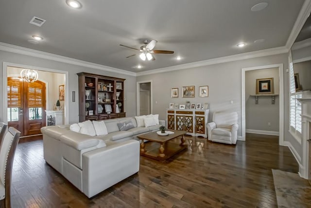 living room with ornamental molding, ceiling fan with notable chandelier, dark wood-type flooring, and visible vents