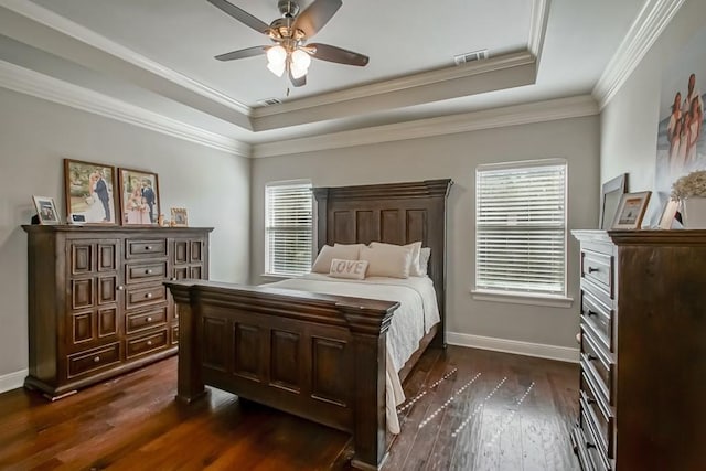 bedroom with visible vents, crown molding, dark wood finished floors, baseboards, and a tray ceiling