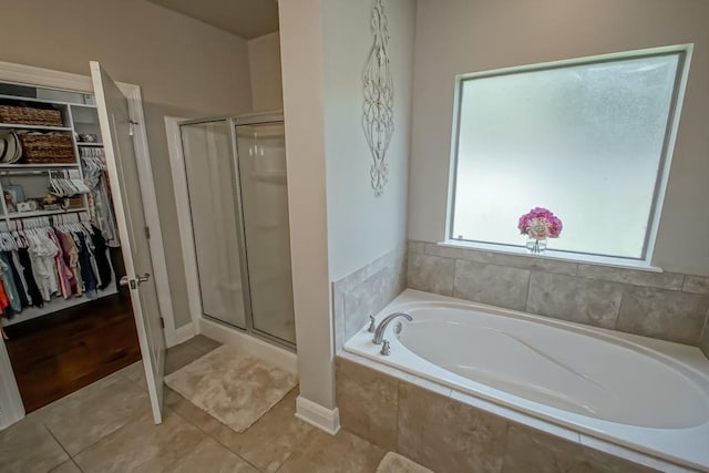 bathroom with a garden tub, a walk in closet, a wealth of natural light, and a shower stall