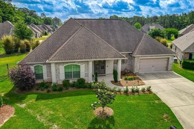 view of front facade featuring fence, a front yard, brick siding, an attached garage, and driveway