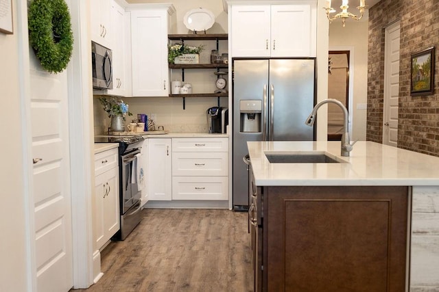 109COUSHATTACIRCLE Coushatta Cir, Madisonville, LA 70447 - kitchen featuring appliances with stainless steel finishes, a sink, open shelves, wood finished floors, and a kitchen island with sink