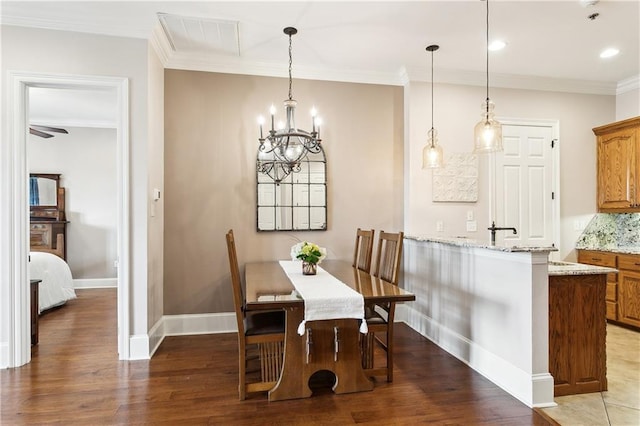 dining room with visible vents, light wood finished floors, crown molding, and baseboards