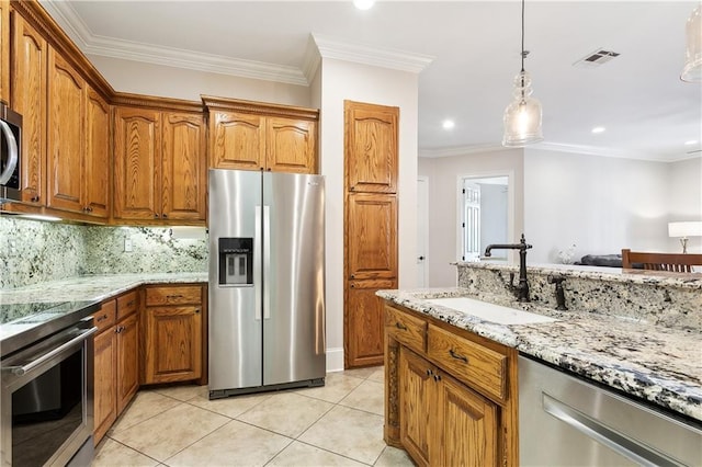 kitchen with visible vents, brown cabinets, light stone counters, a sink, and stainless steel appliances