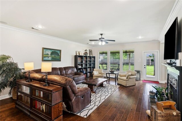 living area with visible vents, ornamental molding, a fireplace, ceiling fan, and dark wood finished floors