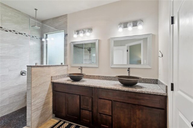 full bathroom with double vanity, a sink, and a walk in shower