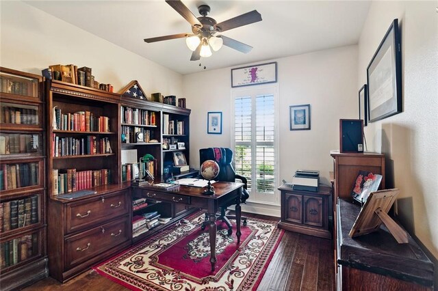 home office with a ceiling fan, baseboards, and dark wood-type flooring
