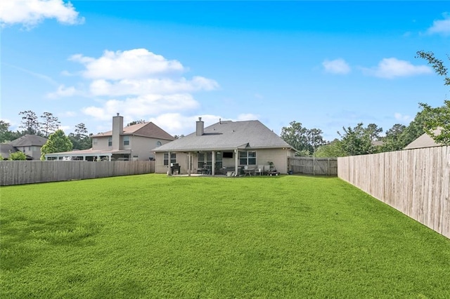 back of house featuring a fenced backyard, a yard, and a patio area