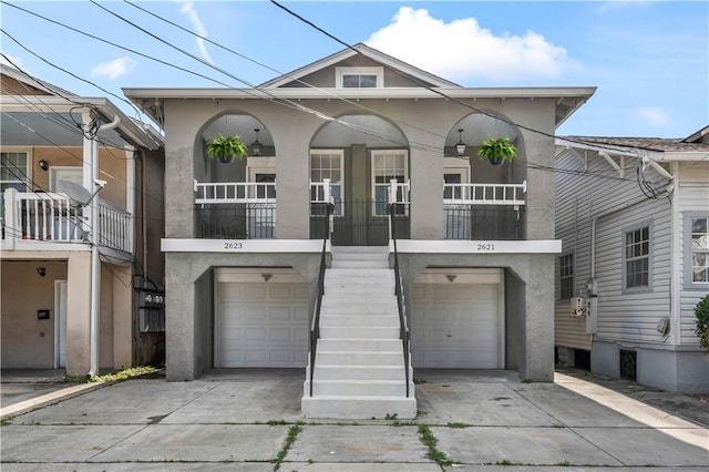 view of front of property with a garage, covered porch, stucco siding, driveway, and stairway