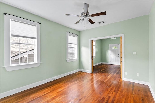 empty room featuring visible vents, plenty of natural light, and hardwood / wood-style floors
