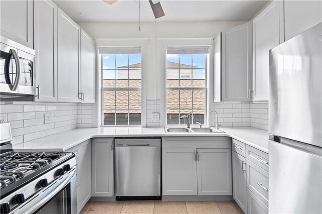 kitchen with a sink, light countertops, ceiling fan, and stainless steel appliances