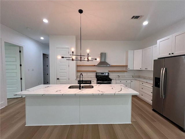 kitchen with open shelves, wood finished floors, a sink, stainless steel appliances, and wall chimney exhaust hood