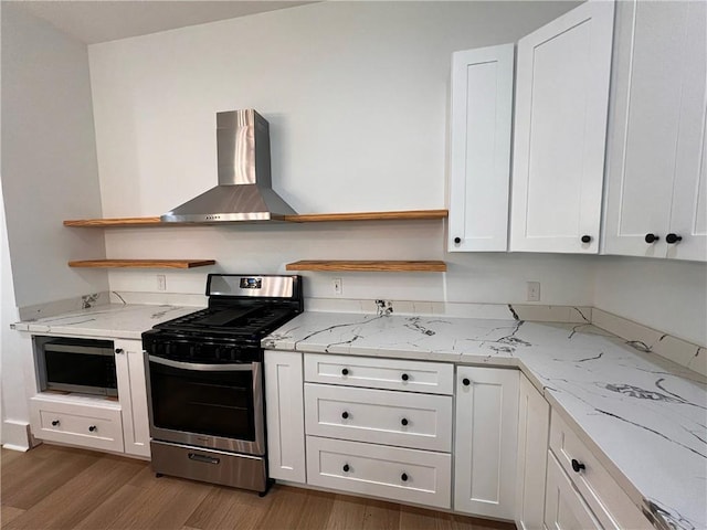 kitchen featuring light wood-type flooring, open shelves, wall chimney exhaust hood, and appliances with stainless steel finishes
