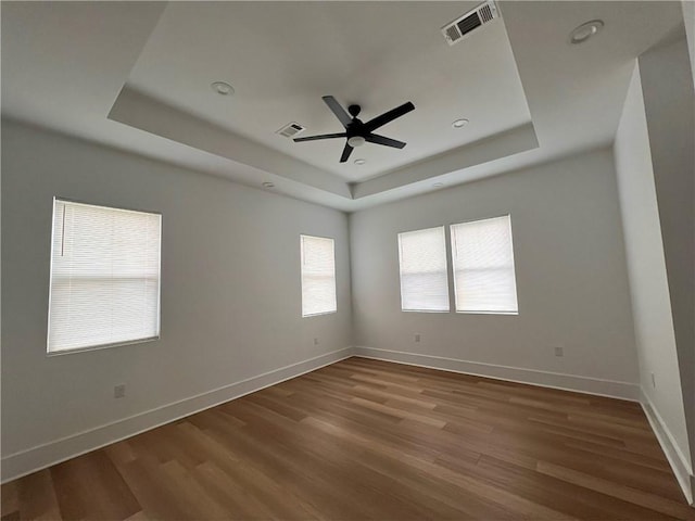 spare room featuring visible vents, a raised ceiling, and wood finished floors