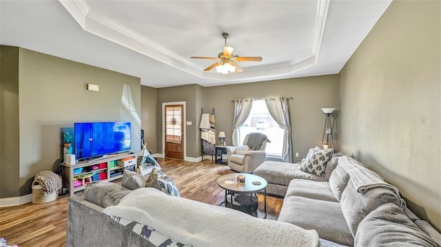 living room with baseboards, a ceiling fan, a tray ceiling, and wood finished floors