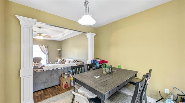 dining space featuring ceiling fan, decorative columns, and a raised ceiling