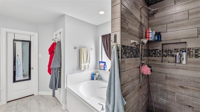 bathroom featuring baseboards, a tile shower, and a bath