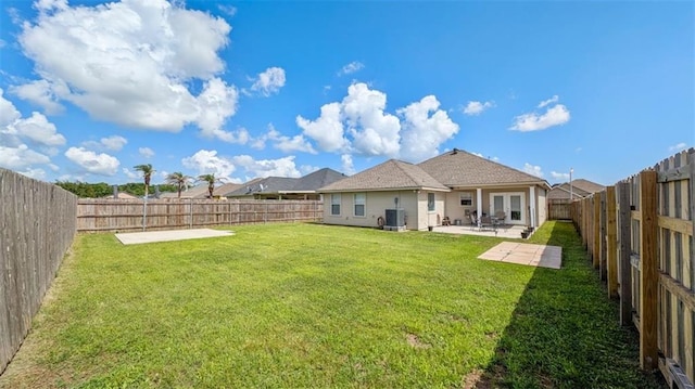 rear view of house with a lawn, central AC unit, a fenced backyard, and a patio area