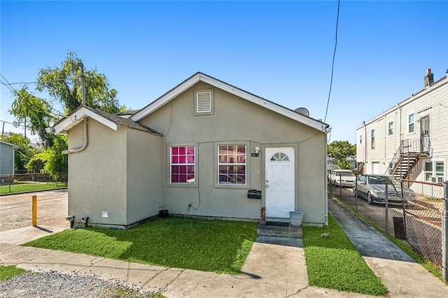 view of front of home featuring stucco siding, a front lawn, and fence