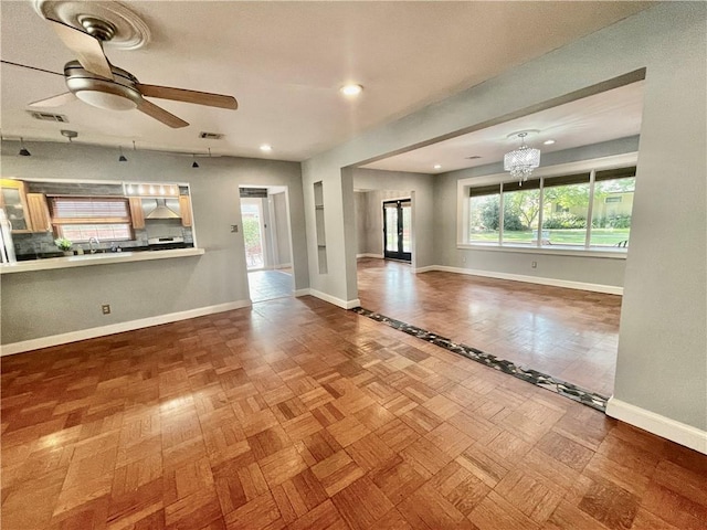 unfurnished living room with baseboards, ceiling fan with notable chandelier, recessed lighting, and visible vents