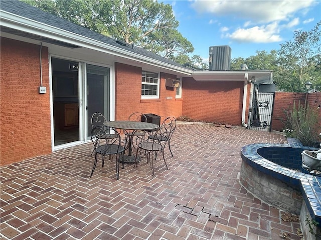 view of patio / terrace with fence, outdoor dining space, a wall mounted air conditioner, a gate, and cooling unit