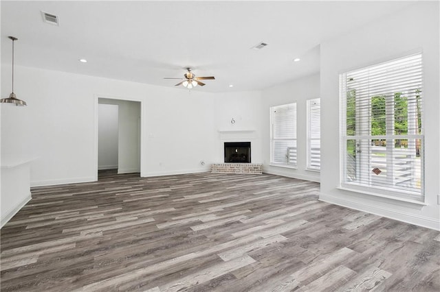 unfurnished living room featuring visible vents, a ceiling fan, baseboards, and wood finished floors