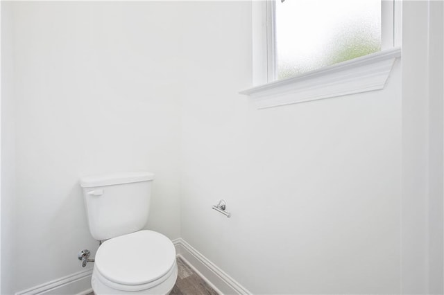 bathroom with toilet, baseboards, and wood finished floors