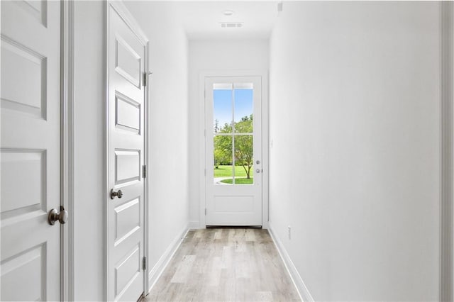 doorway featuring baseboards, visible vents, and light wood finished floors