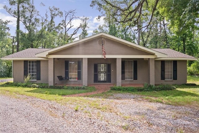 single story home featuring a porch, brick siding, and a front yard
